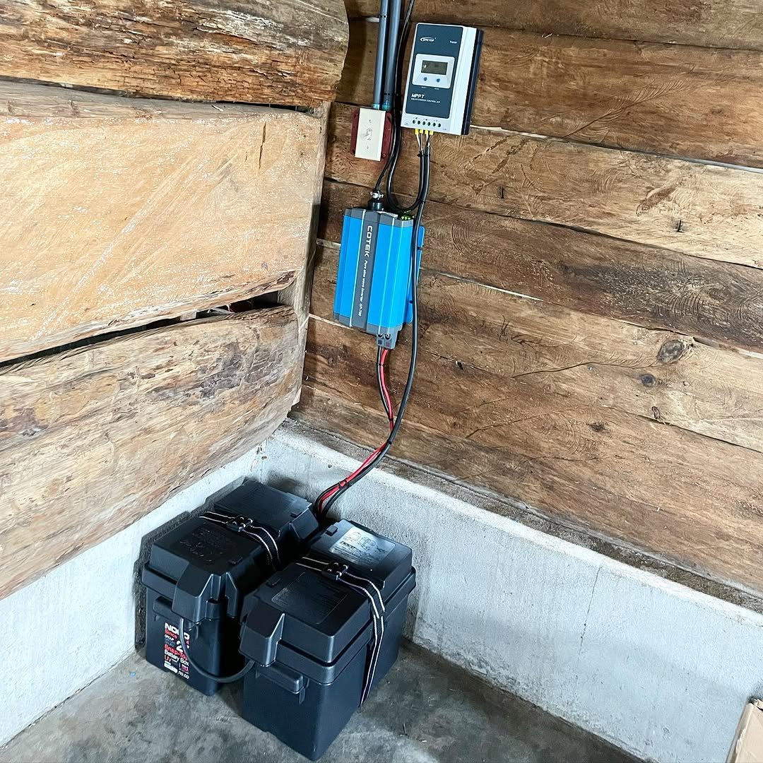 Controlador de carga, inversor y baterías instalados en una cabaña de madera