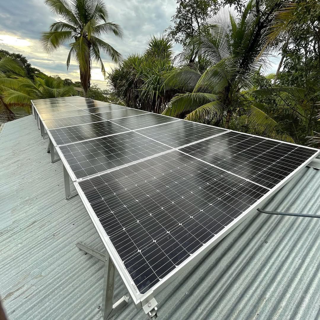 Instalación de paneles solares sobre el techo de una vivienda entre palmeras en Panamá