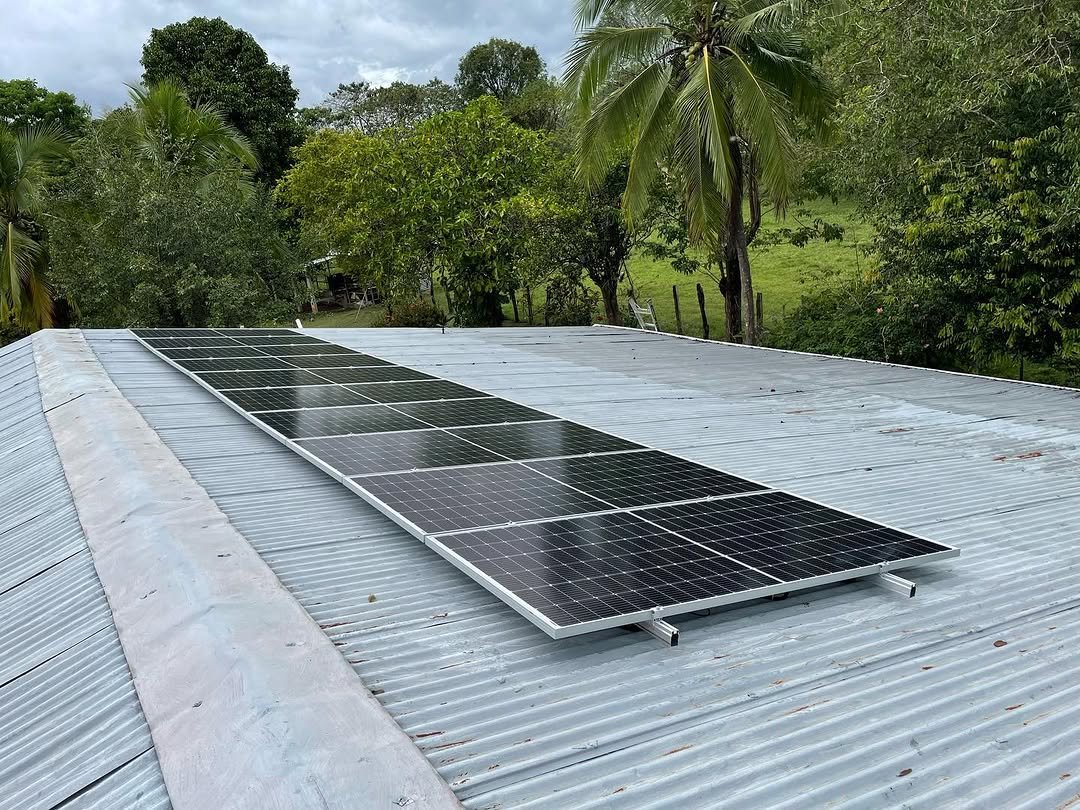 Paneles solares sobre un techo rural rodeado de campo verde en Panamá